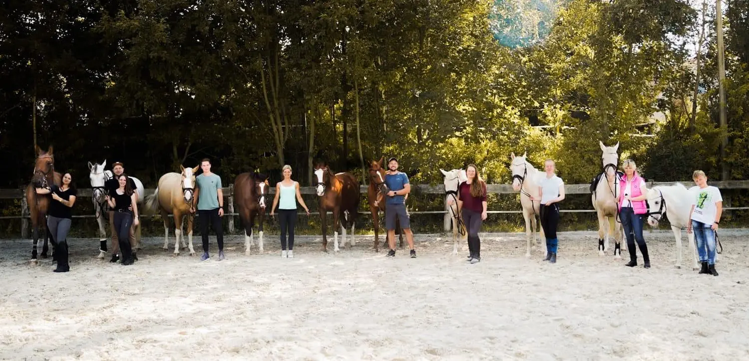 Reitsport Bachmann - Menschen stehen mit ihren Pferden auf dem Pferdehof