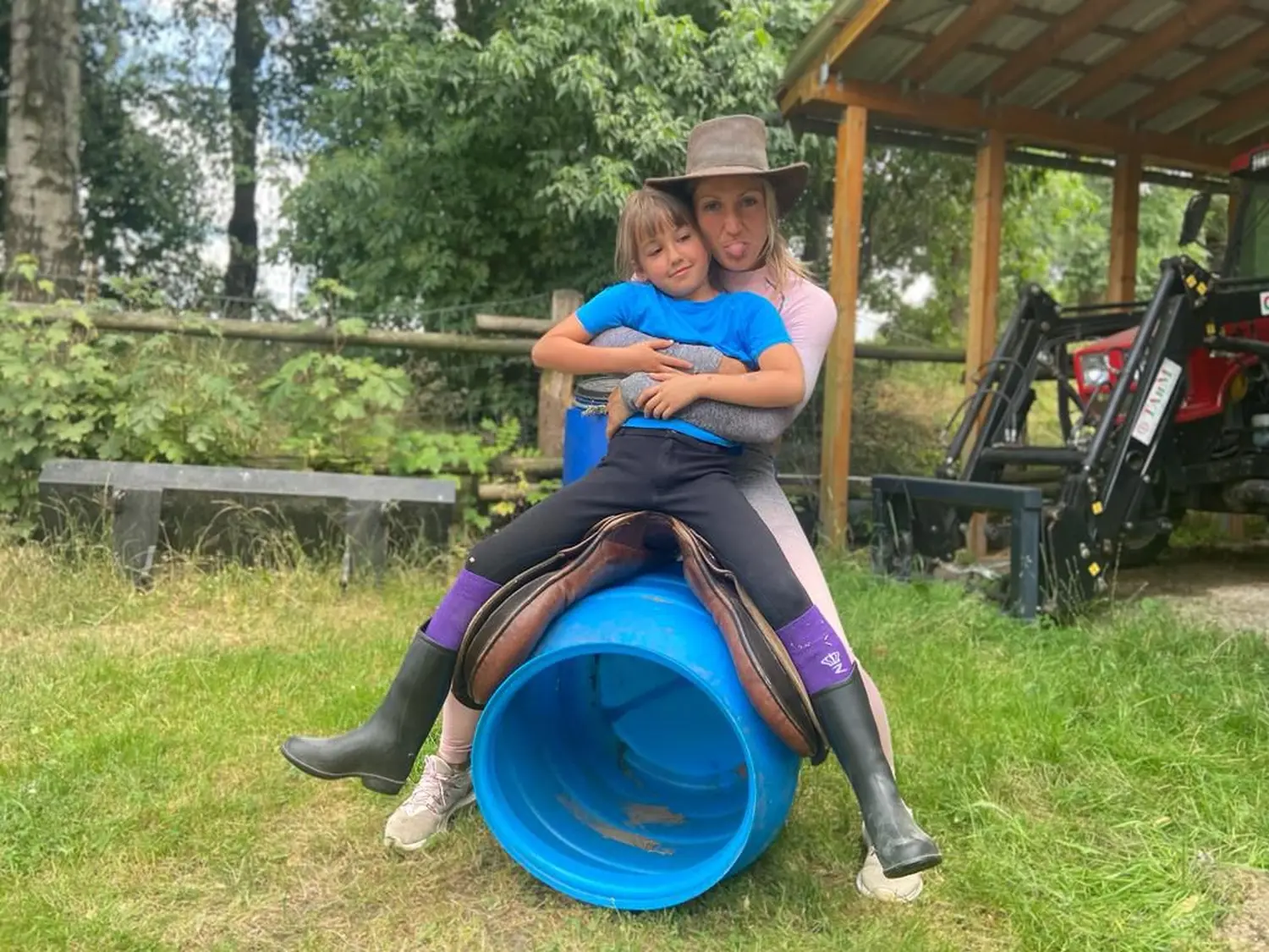 Reitsport Bachmann - eine Frau sitzt mit einem Kind auf einem Schlauch